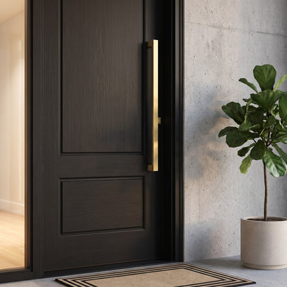 Digital render of the Bluff Bar Pull Handle in brass, shown on a dark timber entrance door beside a concrete wall