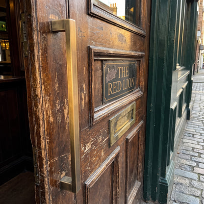 Digital render of the Bluff Bar Pull Handle in bronze, shown on a weathered timber entrance door