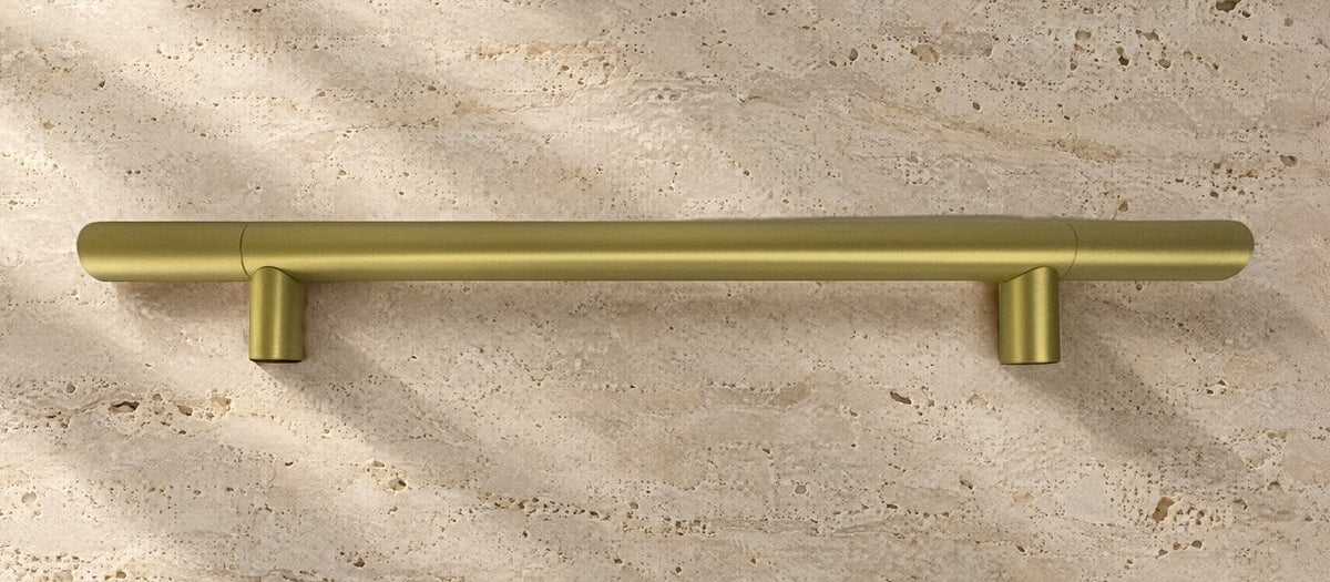 Brass Haast pull handle lying flat on travertine, seen from above, with its overall length and fixing centres marked