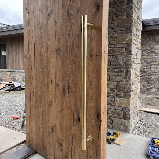Round Tubular pull handle in brass on a timber door