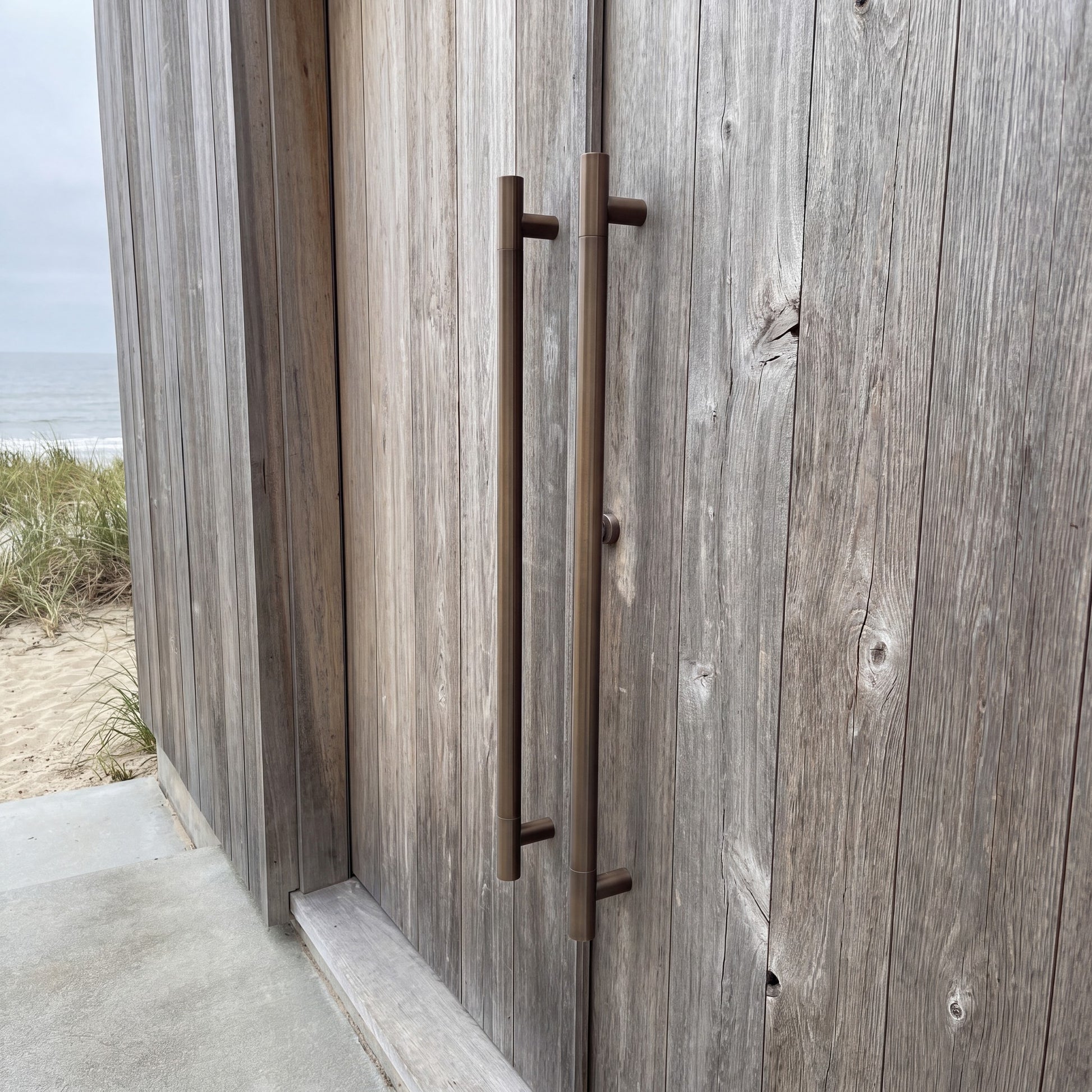 Round Tubular pull handle in bronze on an entrance door