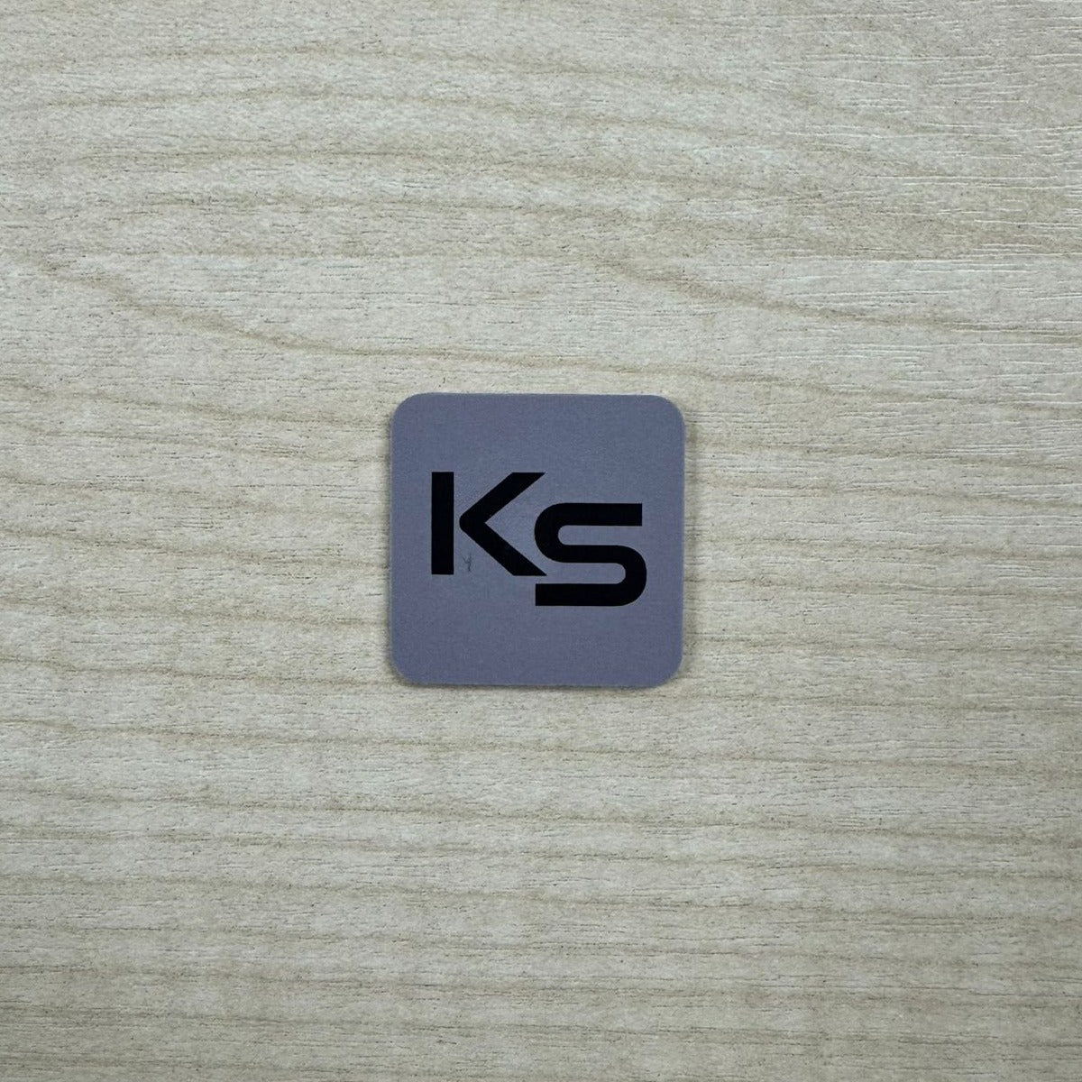 Smart Lock Proximity Dot (Sticky-Back) in grey with the black KS print, a real photo on a timber desk showing its size