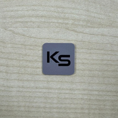 Smart Lock Proximity Dot (Sticky-Back) in grey with the black KS print, a real photo on a timber desk showing its size